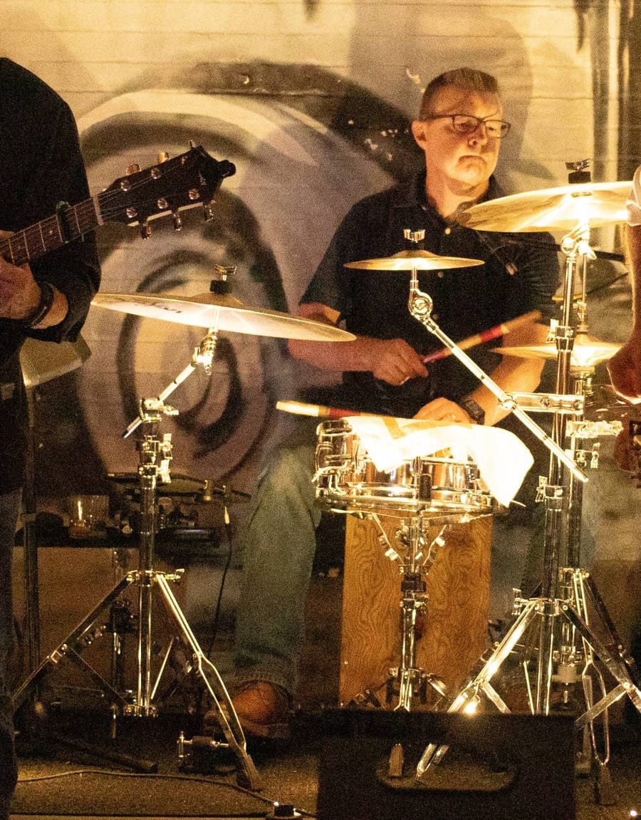 The founder playing drums on stage with a band